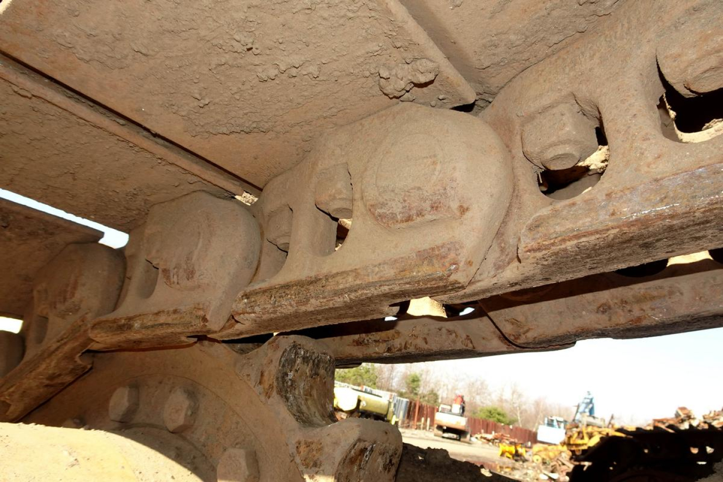 Caterpillar 330L MH undercarriage track roller and bogie with rust and dirt detail, visible steel links and suspension components.