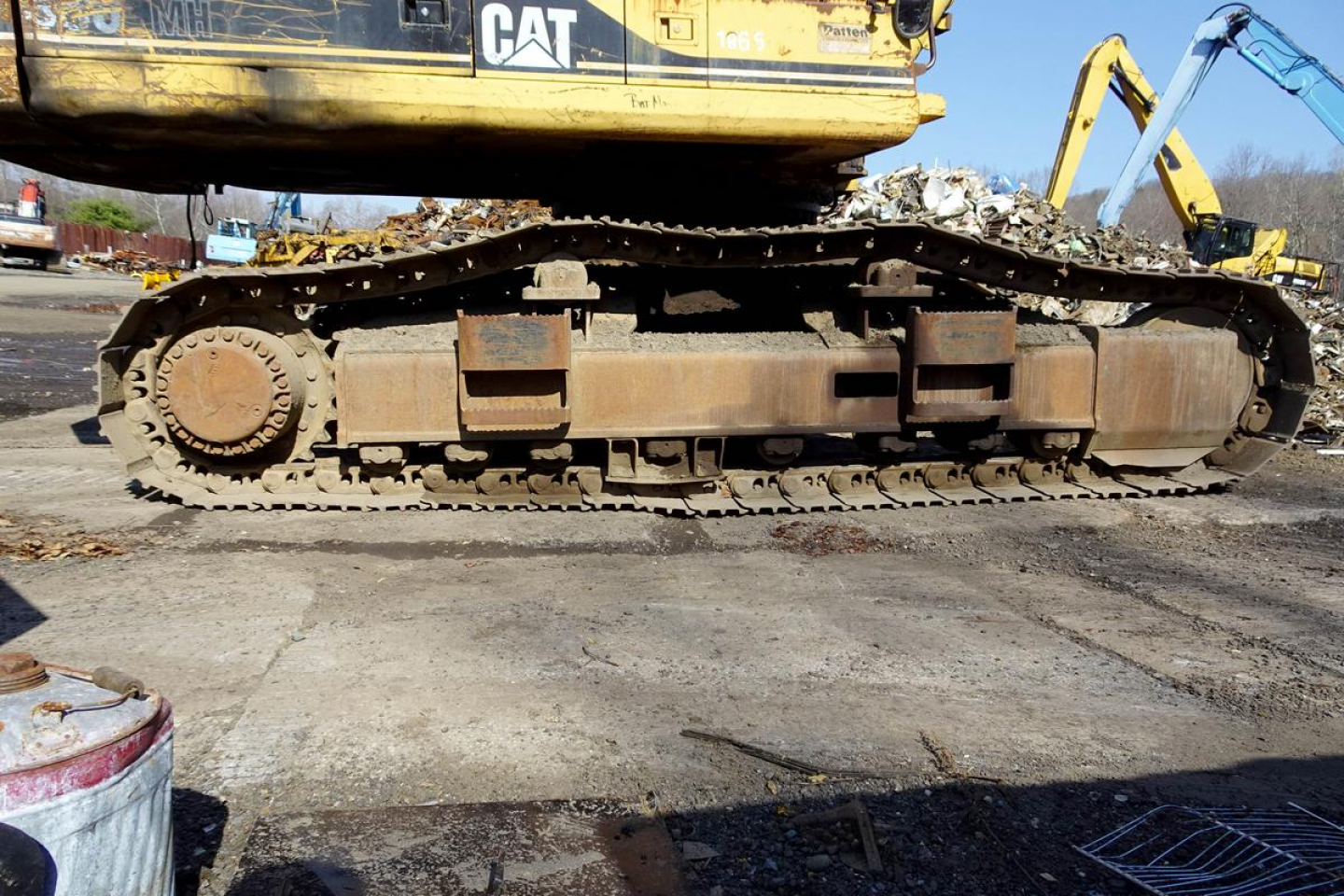 Caterpillar tracked excavator undercarriage showing dirt-covered drive sprocket and track links, with CAT branding on upper structure.