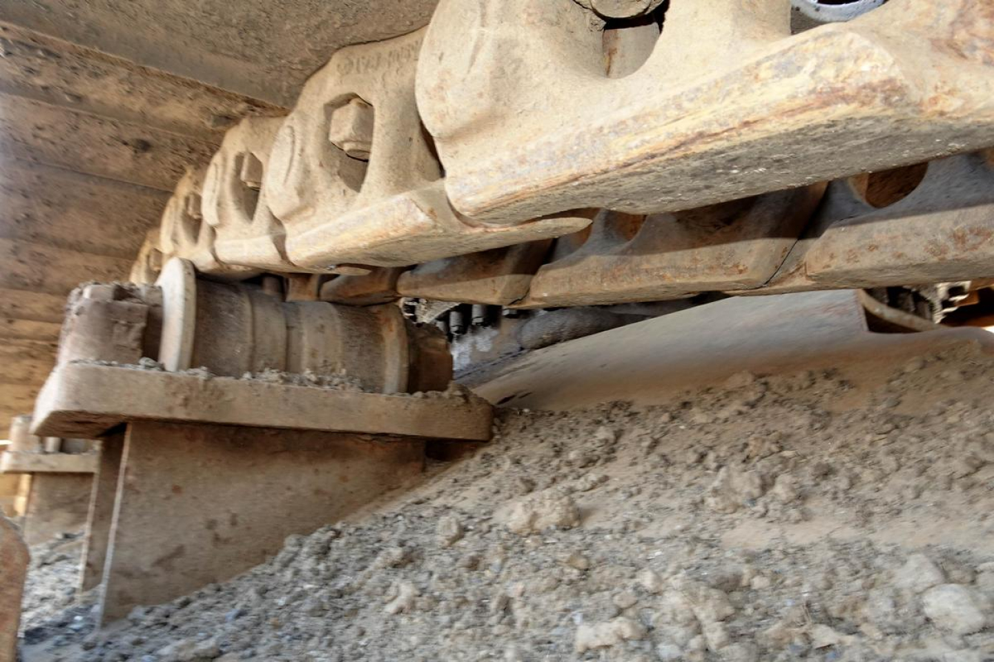 Caterpillar 330L MH tracked undercarriage showing crawler track and undercarriage components in a dirt-covered setting.