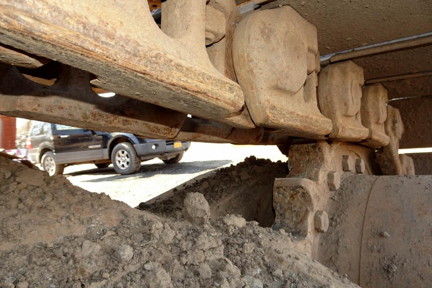 Caterpillar 330L MH undercarriage track system showing bogie rollers and muddy track links.