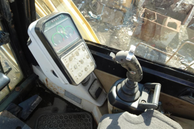 Caterpillar 330L MH cab interior showing joystick control and instrument panel with gauges.