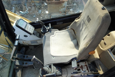 Cab interior of a Caterpillar 330L MH excavator showing operator seat, control levers, and instrument panel with digital display.