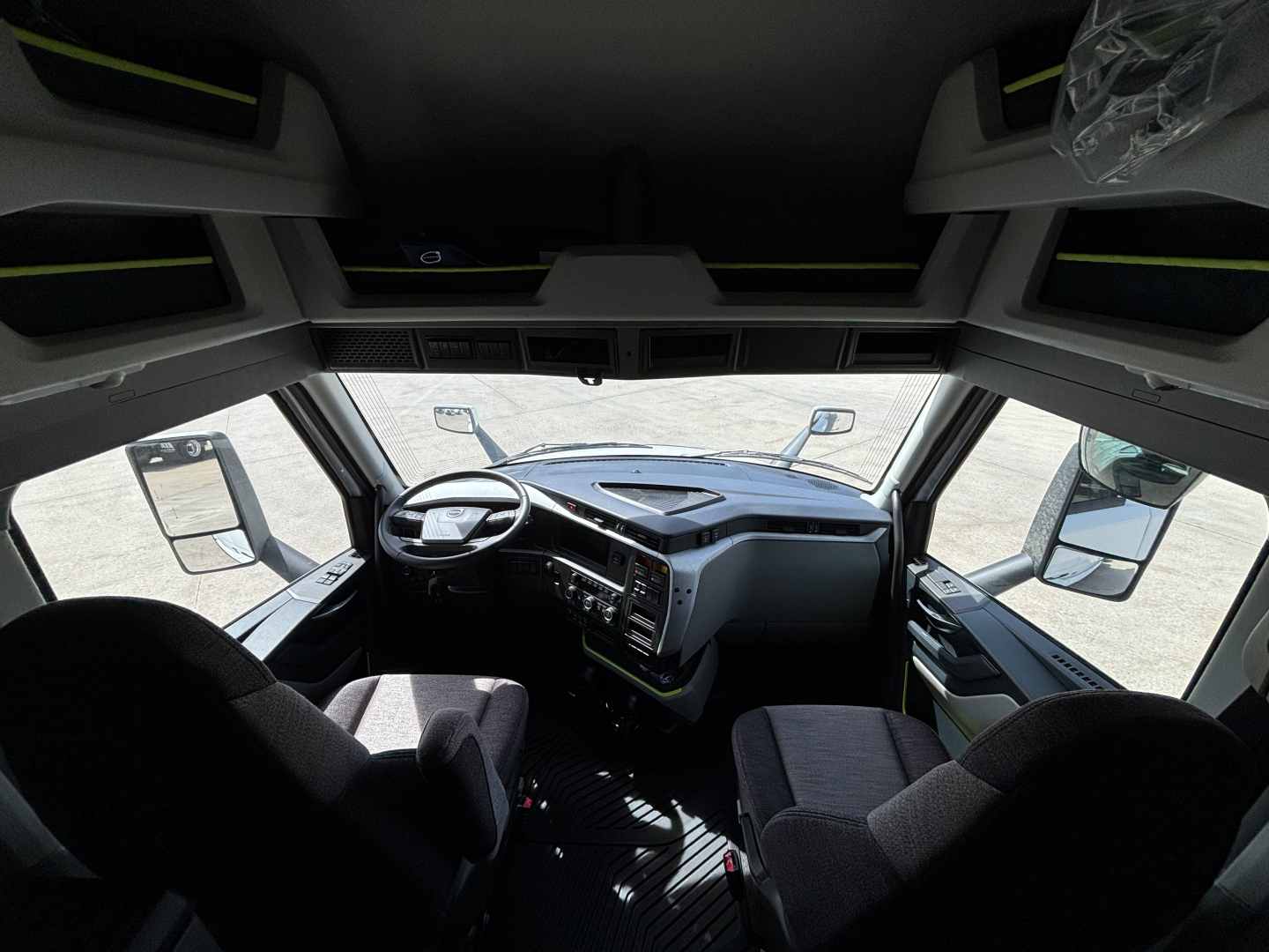 Truck cab interior view of a Volvo VNL64T640 showing steering wheel, dashboard, and front seats.