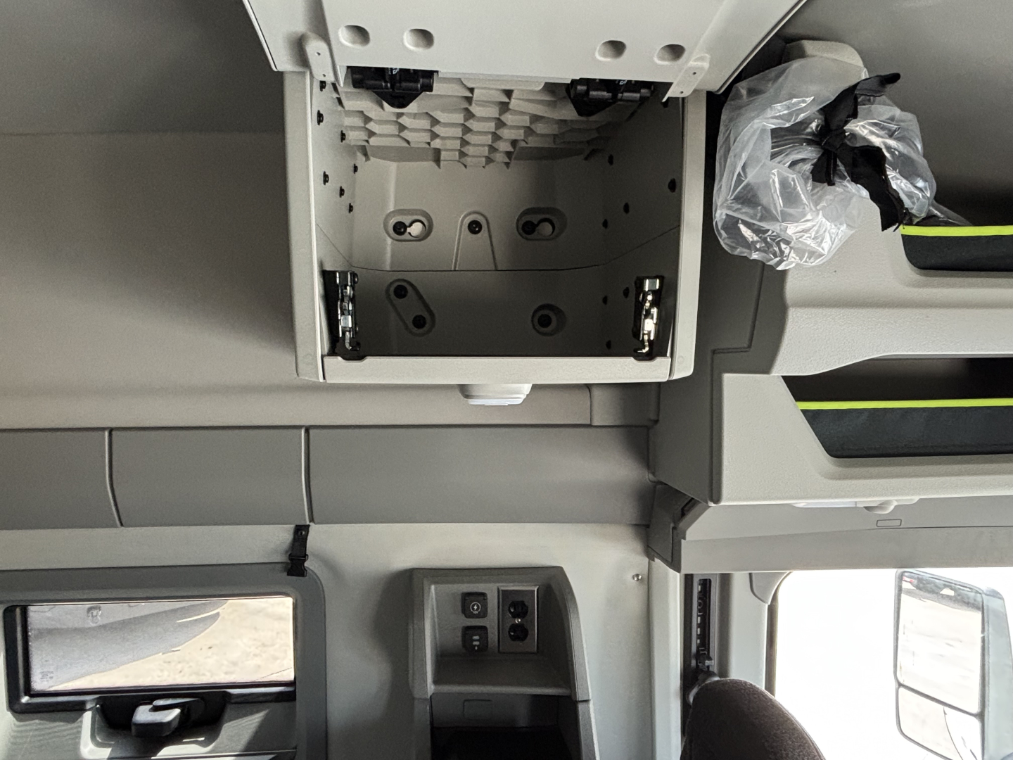Cab interior of a Volvo VNL64T640 showing overhead storage compartment and dash area with control switches near windshield.