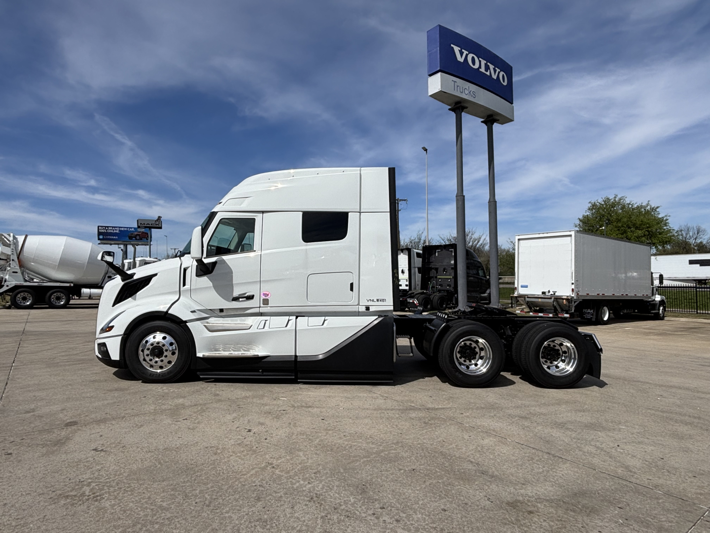 Volvo VNL64T640 tractor shown in side profile with sleeper cab and white paint, at a Volvo Trucks dealership lot.