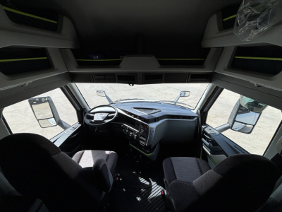 Truck cab interior view of a Volvo VNL64T640 showing steering wheel, dashboard, and front seats.