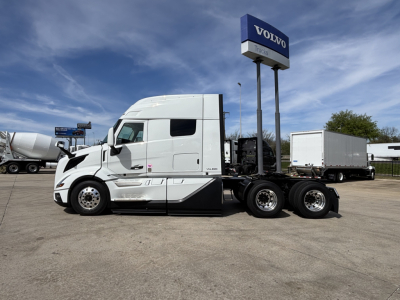 Volvo VNL64T640 tractor shown in side profile with sleeper cab and white paint, at a Volvo Trucks dealership lot.