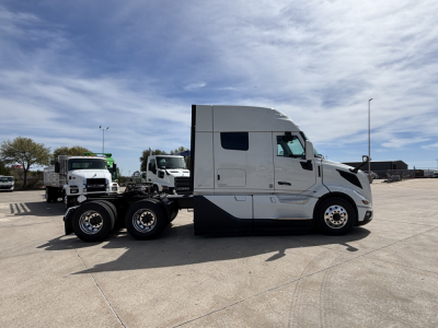 Volvo VNL64T640 truck tractor side view showing sleeper cab and dual rear axles with chrome wheels.