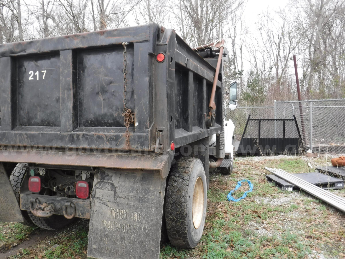 Dump truck rear and side showing bed with '217' stenciled, heavy-duty tires, and rear lights.