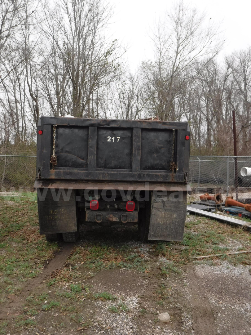 Dump truck bed of a 2011 Ford F-750 seen from rear, tailgate with hydrauilc mechanism and mud flaps.