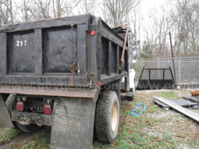 Dump truck rear and side showing bed with '217' stenciled, heavy-duty tires, and rear lights.