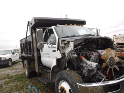 Ford F-750 dump truck engine bay showing exposed engine and radiator with hoses and wiring visible.