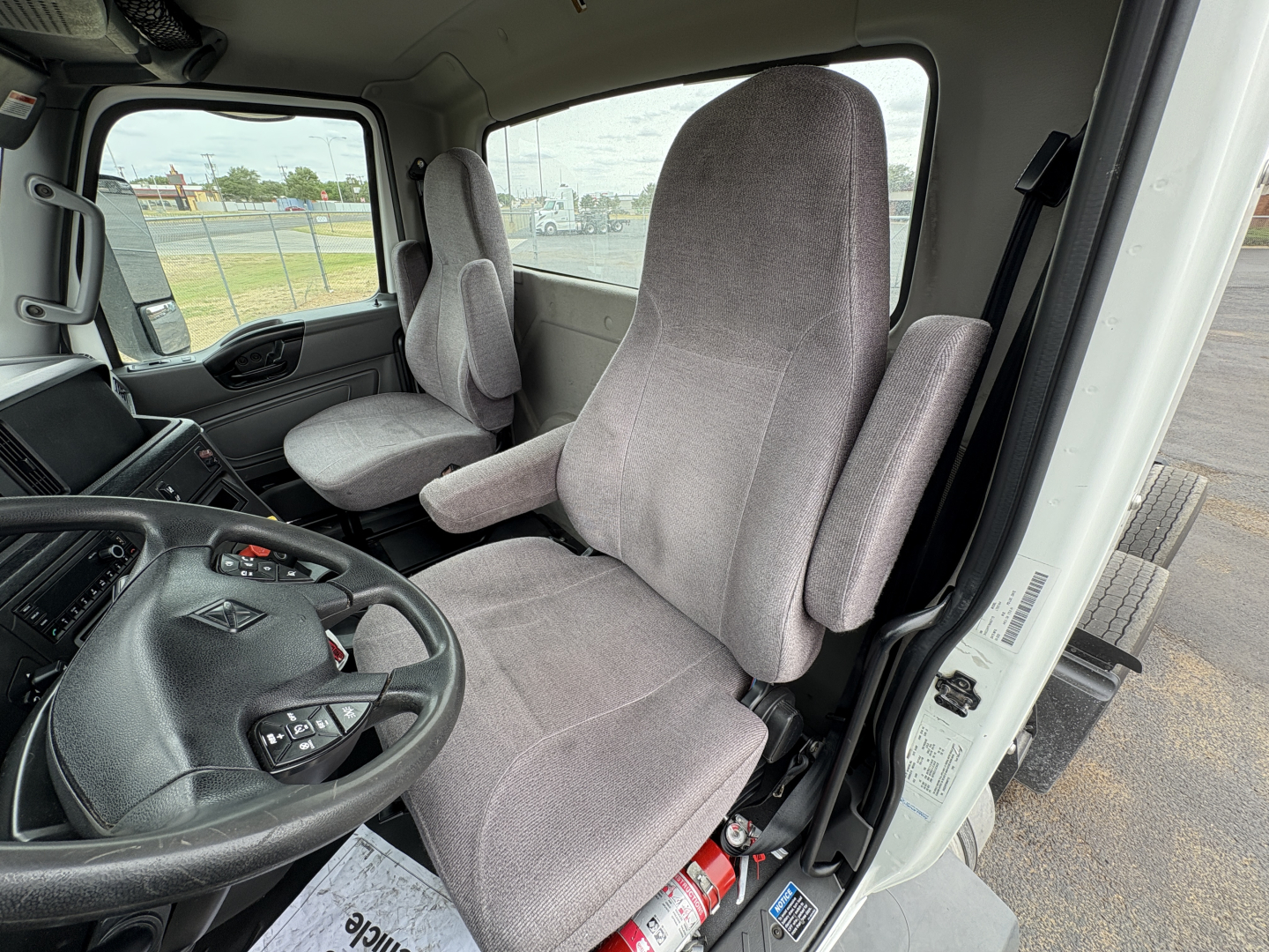 Truck cab interior showing driver and passenger seats with steering wheel and dashboard of a 2021 International LT625 LT cab. Visible text on dashboard and controls but no clear model-specific labels.