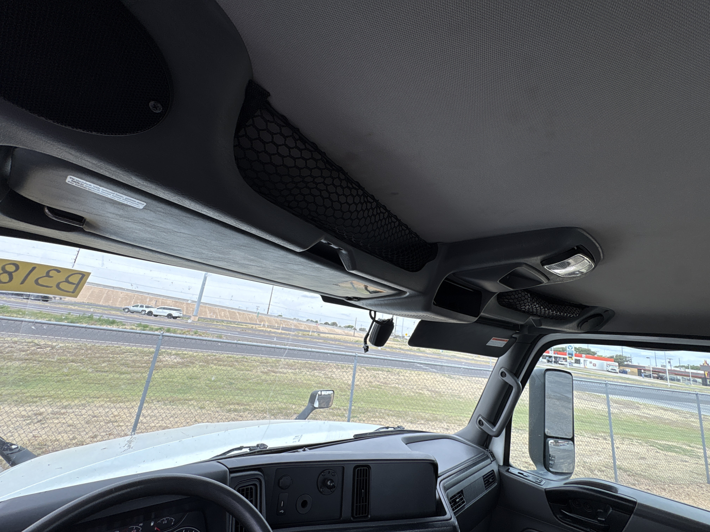 Cab interior of a 2021 International LT625 daycab truck showing steering wheel, dashboard, sun visors, and side window with outside lot.