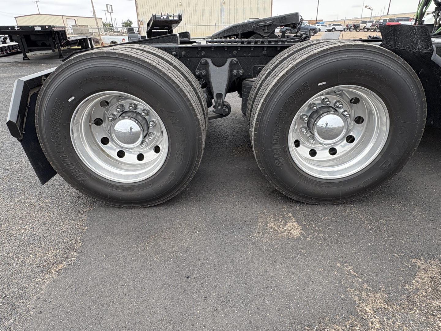 Dual rear axle with large wheels on a Class 8 truck chassis showing polished aluminum rims and hub covers.