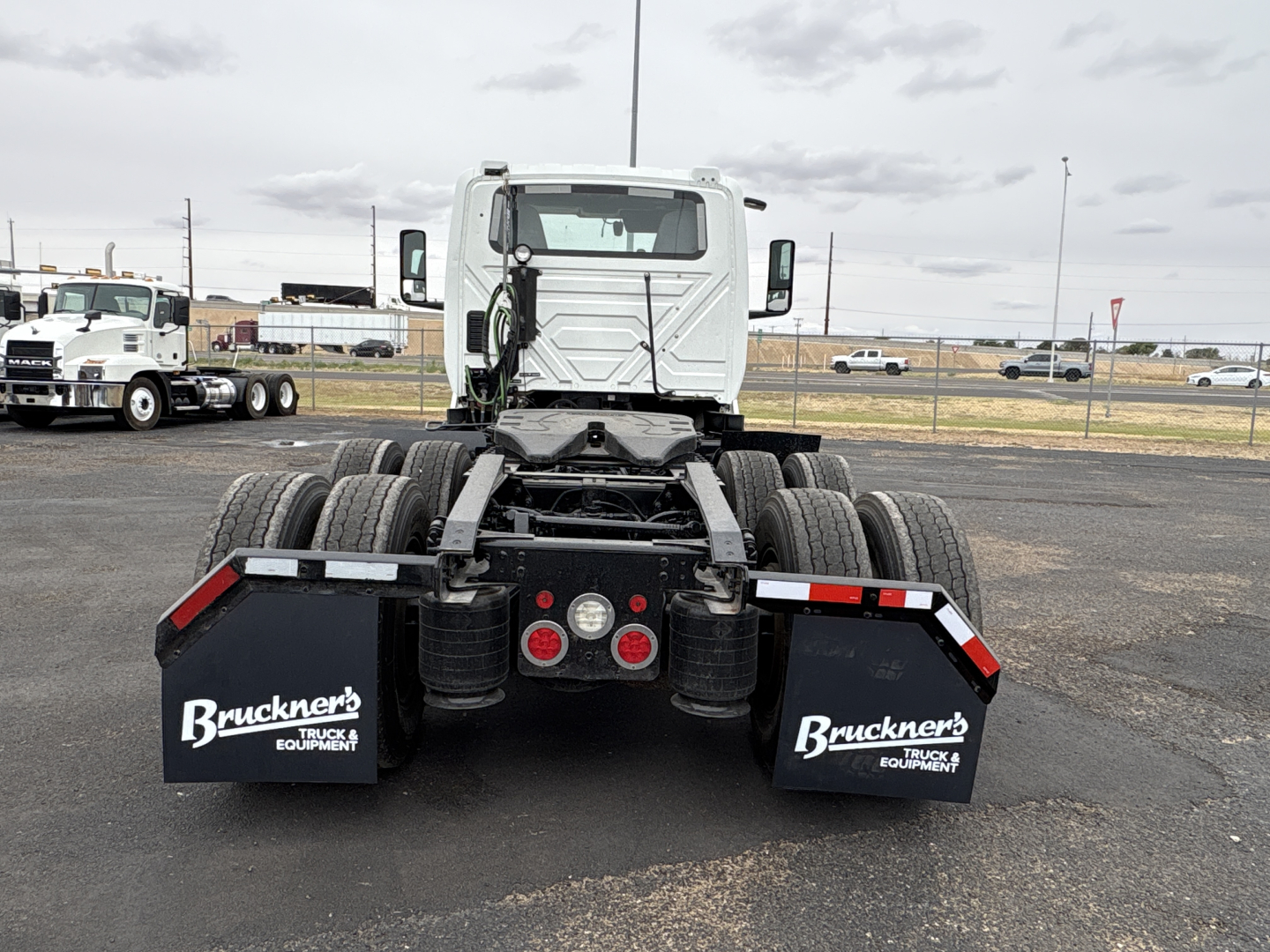 Rear view of a white 2021 International LT625 truck tractor showing dual rear axles, mud flaps with Bruckners logo, and red taillight hubs.