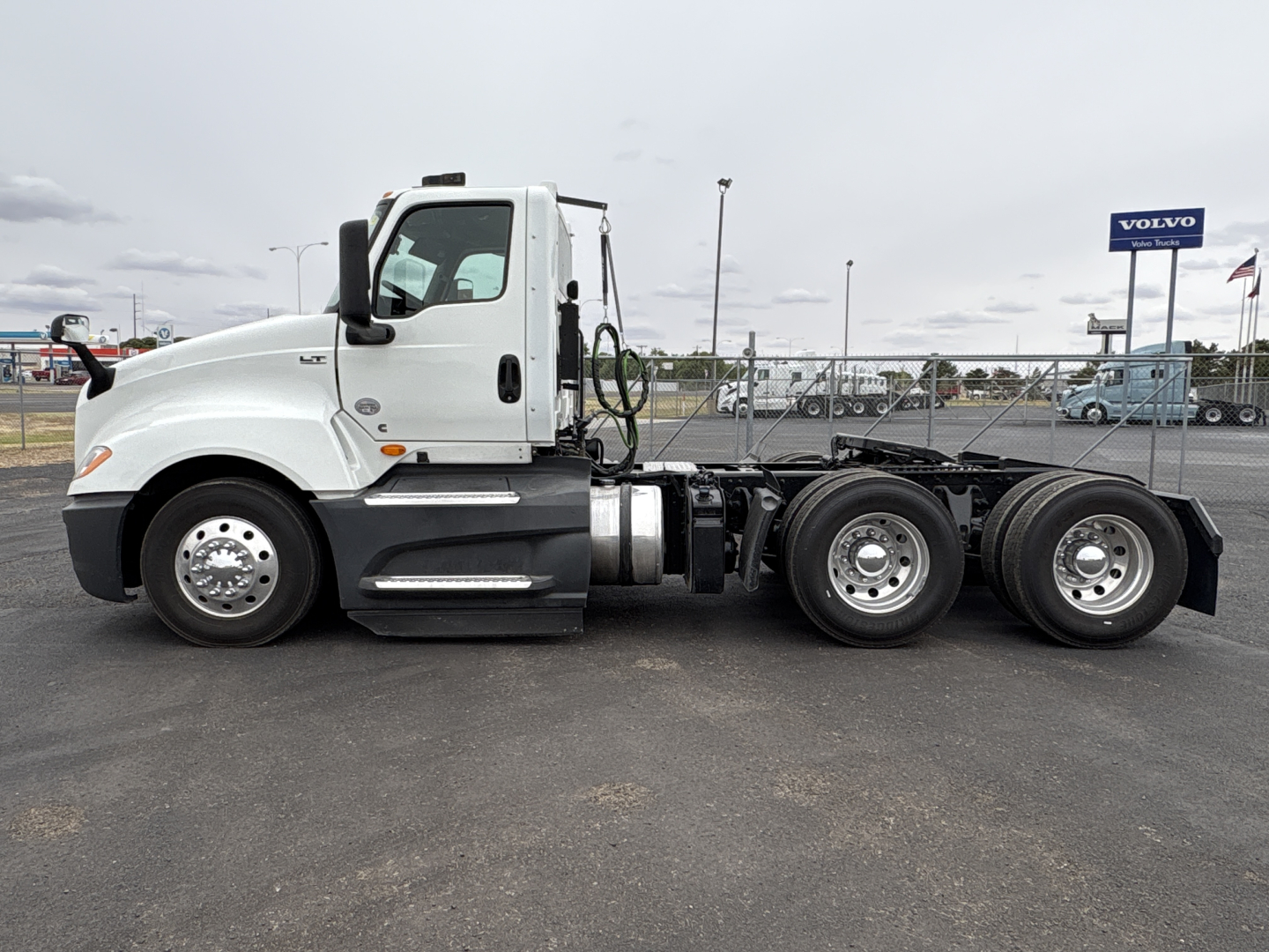 Truck side profile showing a white cab and chassis of a 2021 International LT625 with three axles and dual rear wheels.