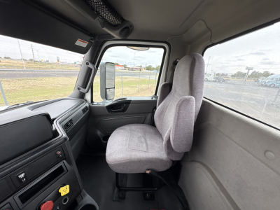 Interior of a used 2021 International LT625 daycab truck cab with grey fabric seats and steering wheel visible.
