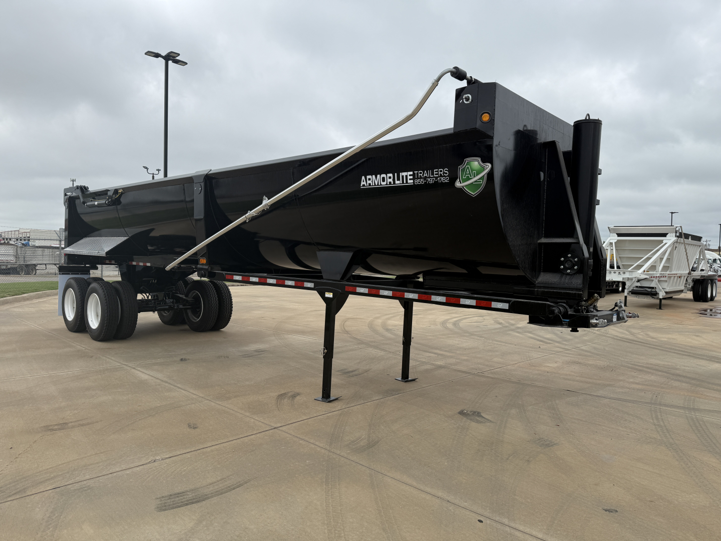 Armor Lite SHD32/48 dump trailer in-service with hydraulic lift and side rails, black with white branding, side profile view.