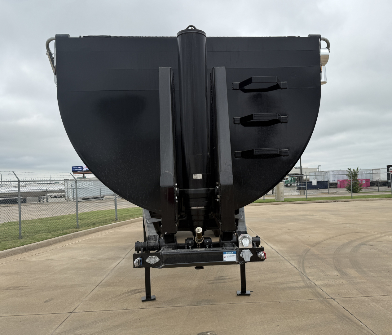 Dump trailer front view showing black Armor Lite SHD32/48 with rear stabilizer legs and hitch assembly.
