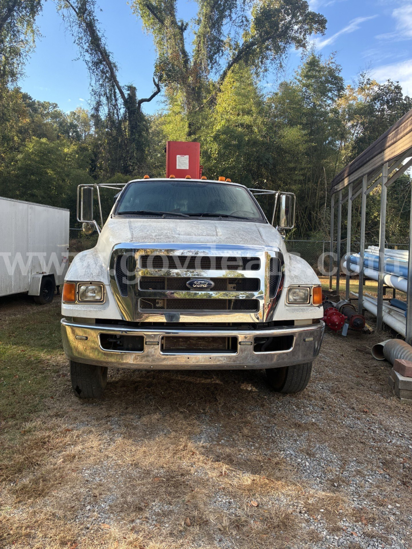 Ford F-750 grapple truck front view showing chrome bumper and Ford emblem, daytime outdoor lot.