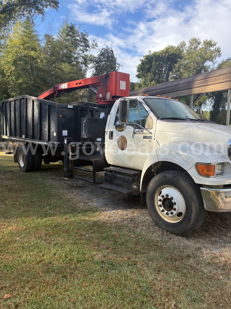 2013 Ford F-750 dump truck with grapple crane in bed, VIN 3FRXF7FJ8DV028103, stock 41-97, used. Large black dump body, red boom crane, white cab.