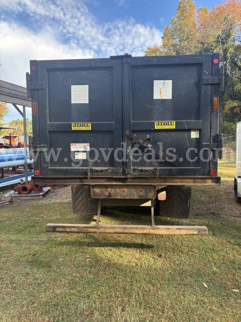 Rear view of a used 2013 Ford F-750 grapple truck with a black dump body and safety labels, stock number 41-97, VIN 3FRXF7FJ8DV028103.