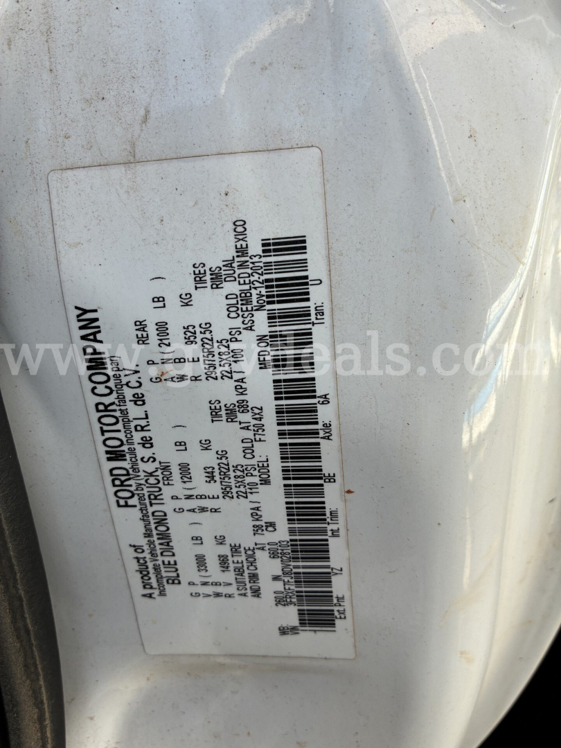 Ford Motor Company compliance label with vehicle specs on a white truck frame; barcode and small print text visible on sticker.