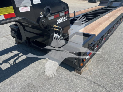 Trailer rear corner showing 35GSL lettering on black hitch assembly and wooden deck of a lowboy trailer, with hydraulic hoses and mounting hardware visible.