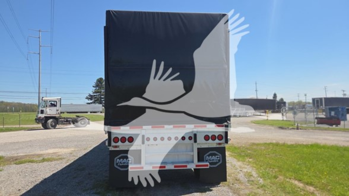 Mac Aluminum flatbed trailer rear view with black tarpaulin and white graphic of hands. Lights and reflective tape on bumper.