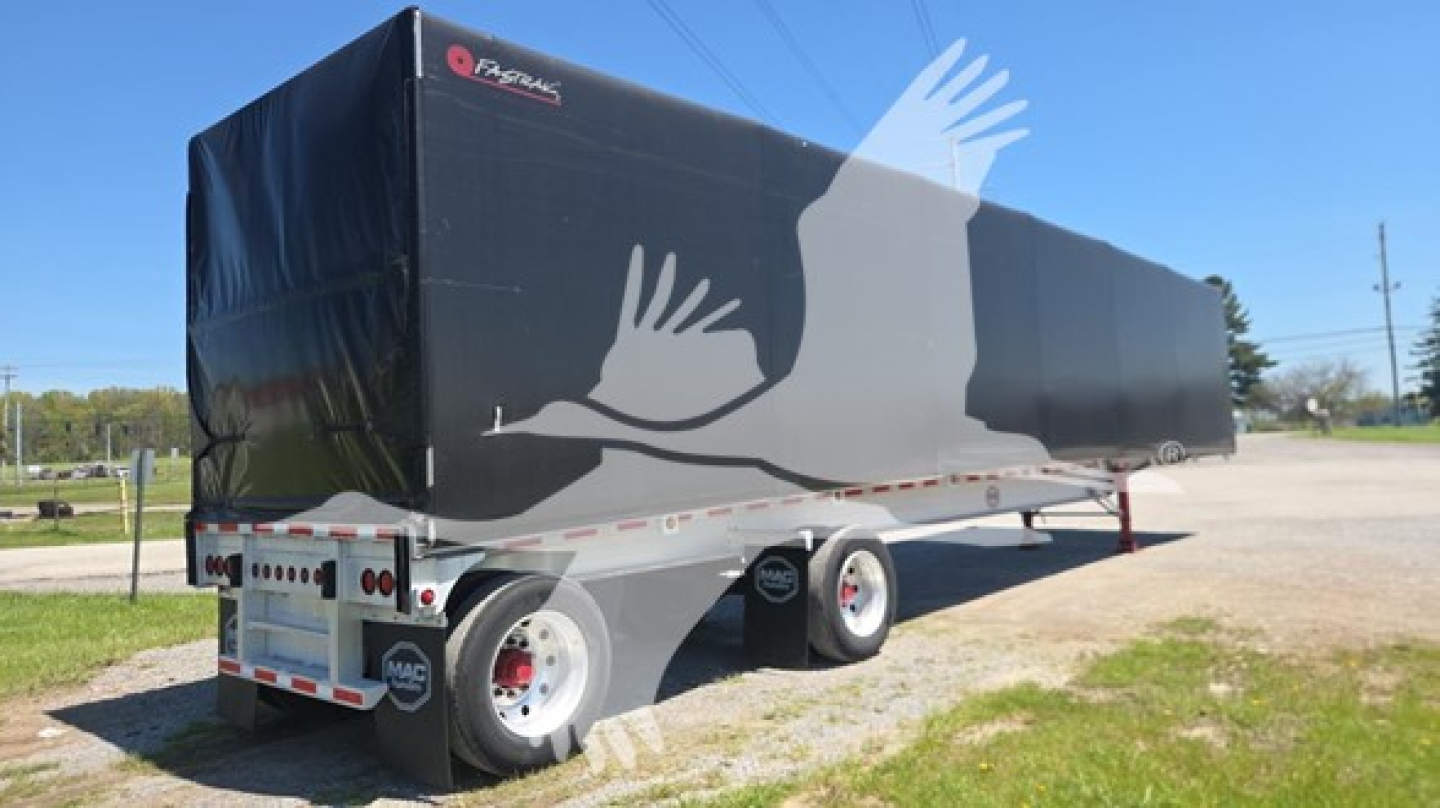 Mac aluminum flatbed trailer with black curtain side and cover showing 'Mac' logo and white graphic across side, dual axle setup.