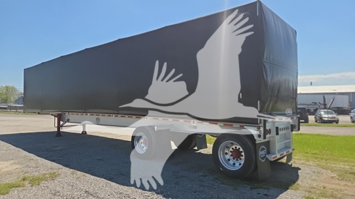Curtainside trailer in service with a large graphic of white flying birds on the tarp and dual rear wheels visible.
