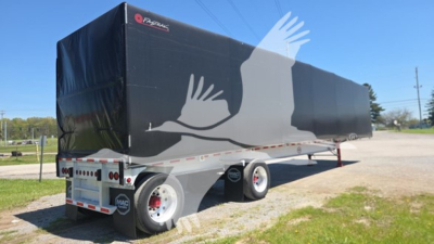 Mac aluminum flatbed trailer with black curtain side and cover showing 'Mac' logo and white graphic across side, dual axle setup.