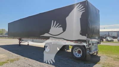 Curtainside trailer in service with a large graphic of white flying birds on the tarp and dual rear wheels visible.