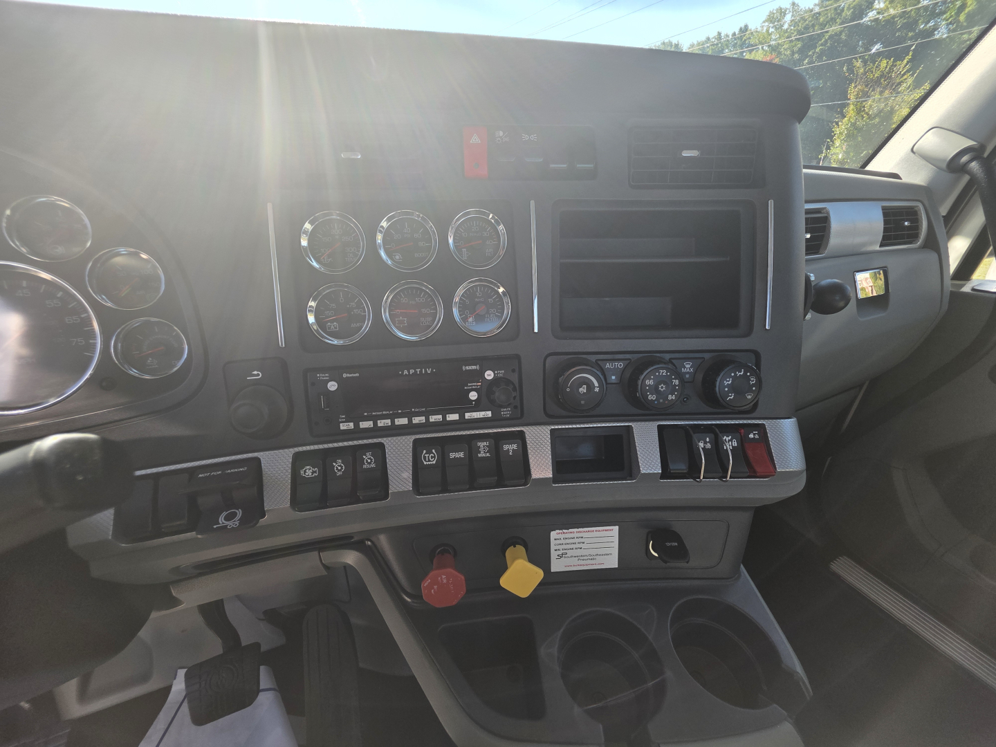 Kenworth T880 truck cabin dash showing multiple analog gauges, center console, climate controls, and switch panel.