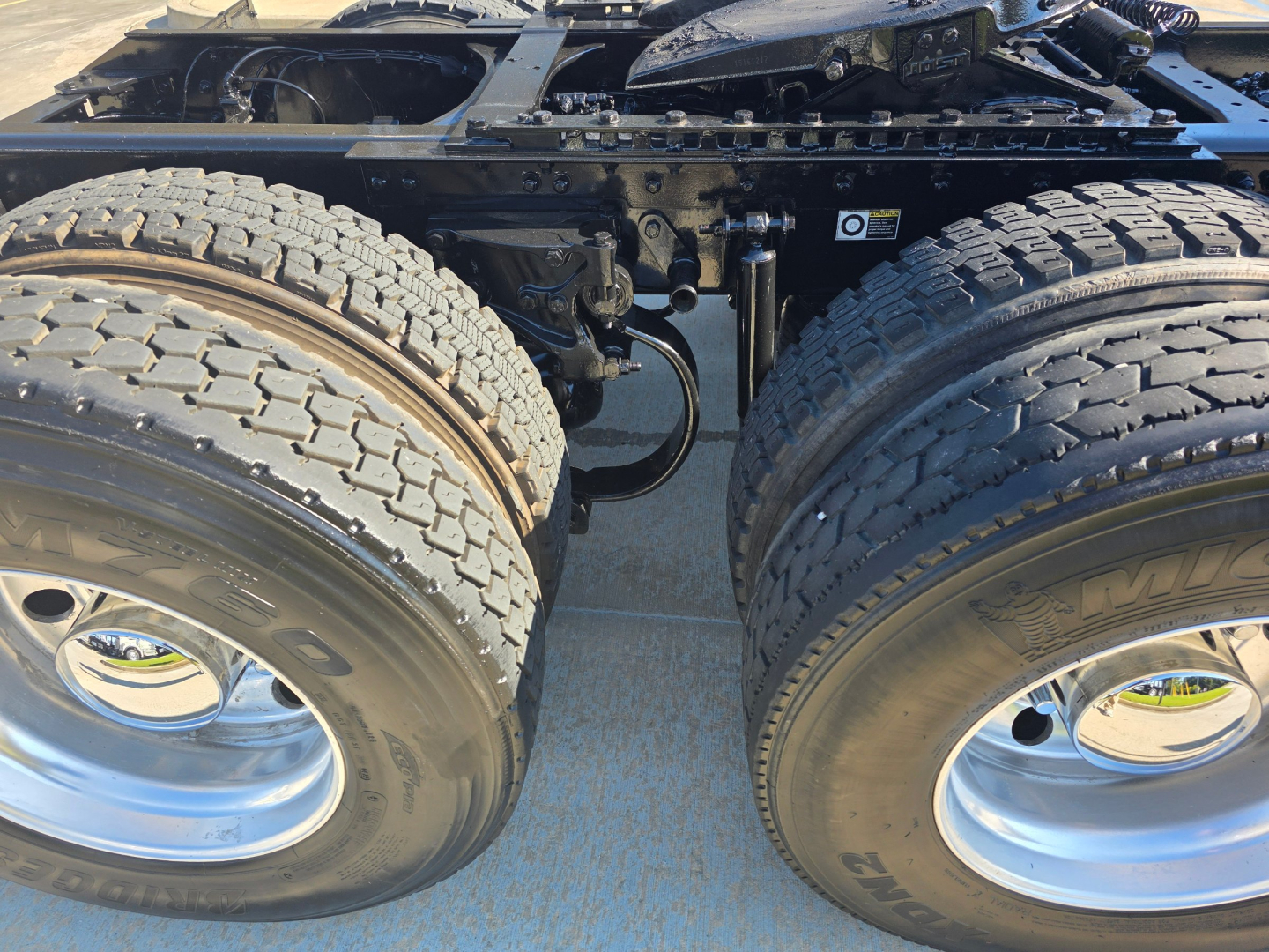 Kenworth T880 truck chassis with dual rear axles and exposed suspension components; tires and rims visible; chassis and undercarriage in view.