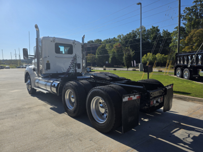 Kenworth T880 tractor unit rear view showing dual rear axles, fifth wheel, chrome fuel tanks, and exhaust stacks.