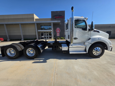 Kenworth T880 truck side profile showing cab, fuel tanks, and chassis with six rear wheels in a dealership lot.