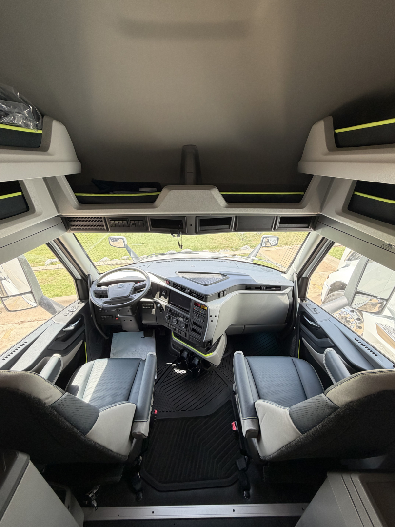Interior of Volvo VNL64T860 cab showing steering wheel, dashboard, and front seats from a high-angle view.