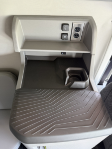 Cabin area of a Volvo truck interior showing a built-in storage pocket, USB/AC outlets, and a fold-out step with a ribbed surface.