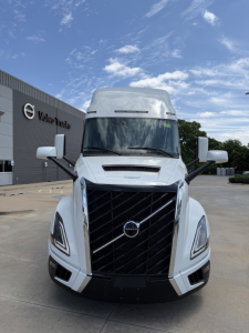 Front view of a new white Volvo VNL64T860 conventional sleeper truck with large grille, Volvo logo, and side mirrors.