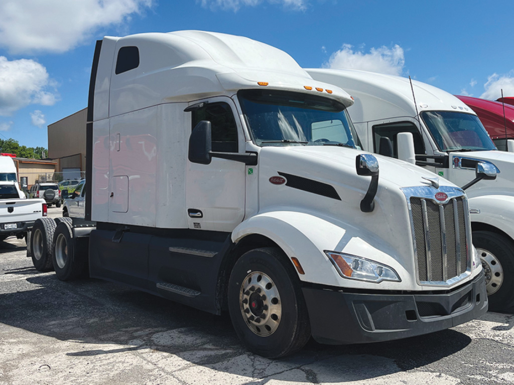 Peterbilt 579 sleeper cab tractor in white, side view showing front grille, headlights, and aerodynamic design