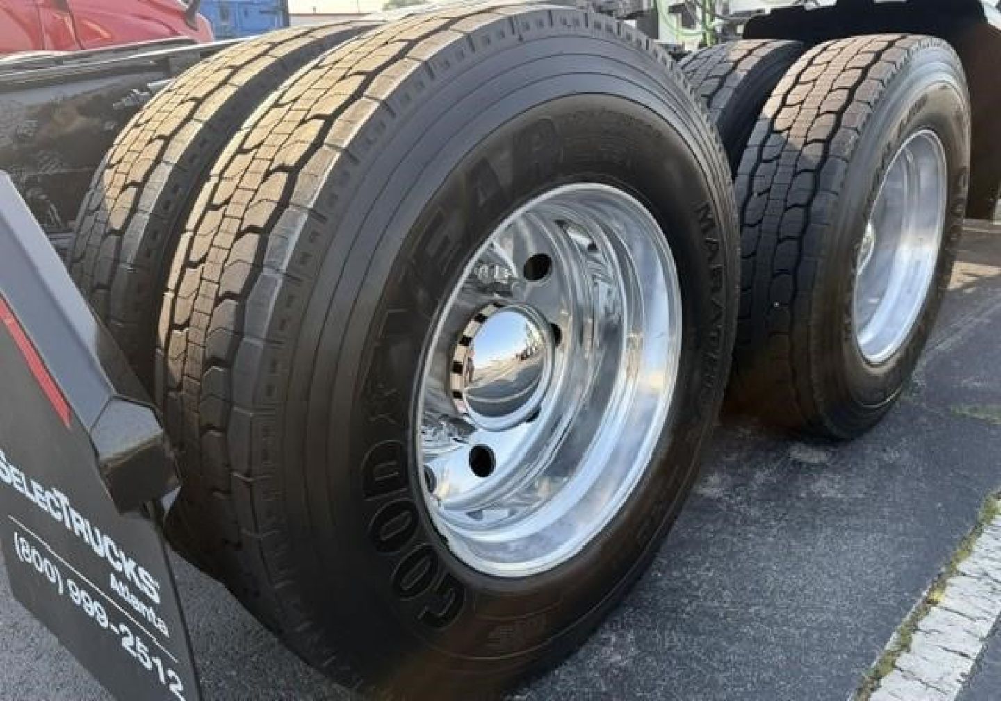 Dual rear axles with Goodyear tires and chrome wheels on a Freightliner Cascadia 126 truck, wheel rims visible; partial trailer hitch area and fender with markings.