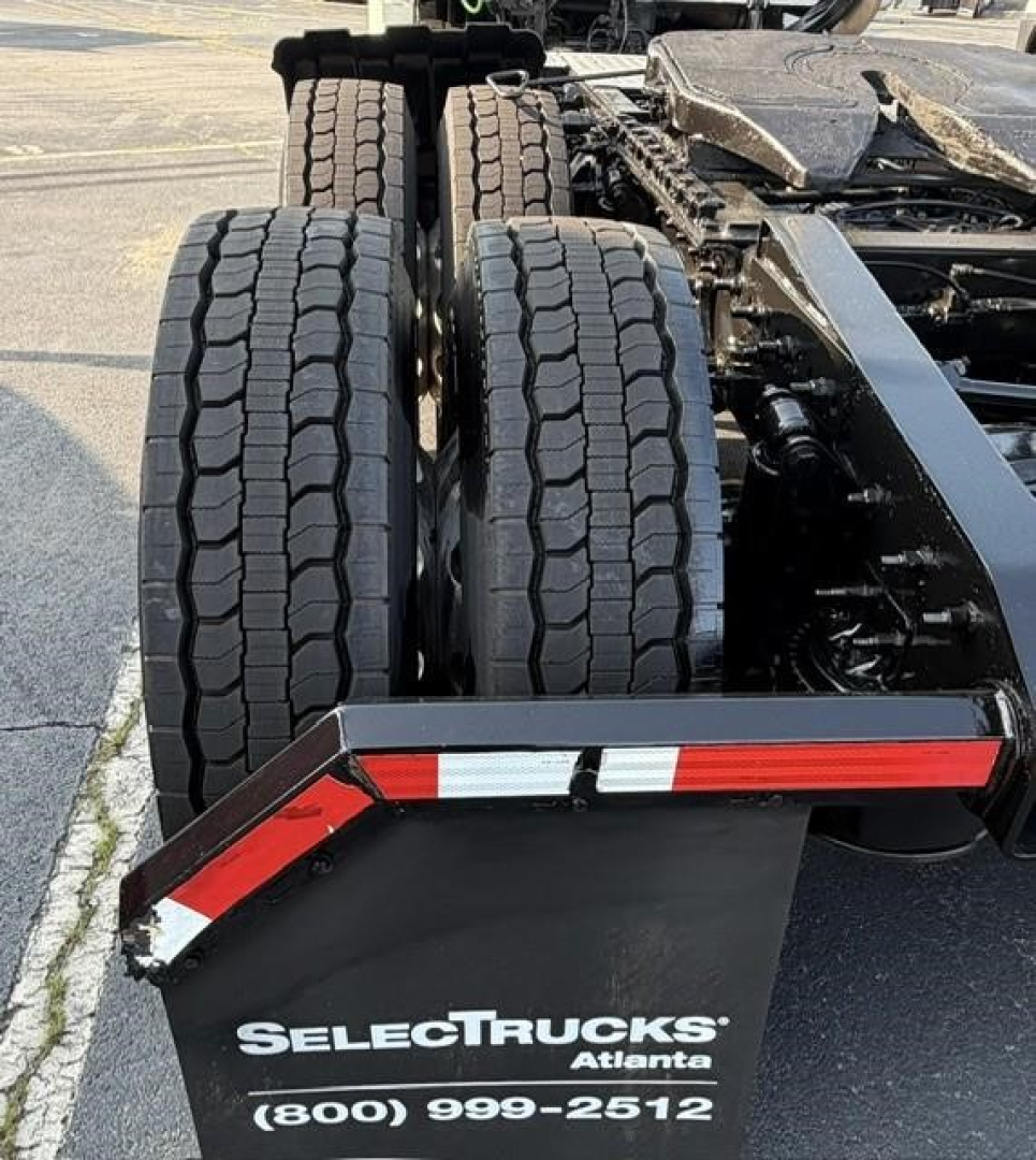 Rear view of a Freightliner Cascadia 126 truck showing dual rear axles and fifth wheel; SelectTrucks Atlanta branding on mudguard with phone number.