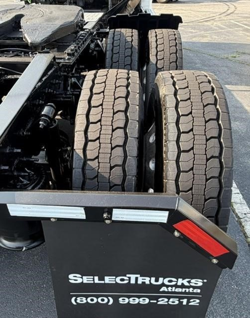 Freightliner Cascadia 126 chassis showing double rear tandem tires and part of the frame with a SelectTrucks sign in foreground.