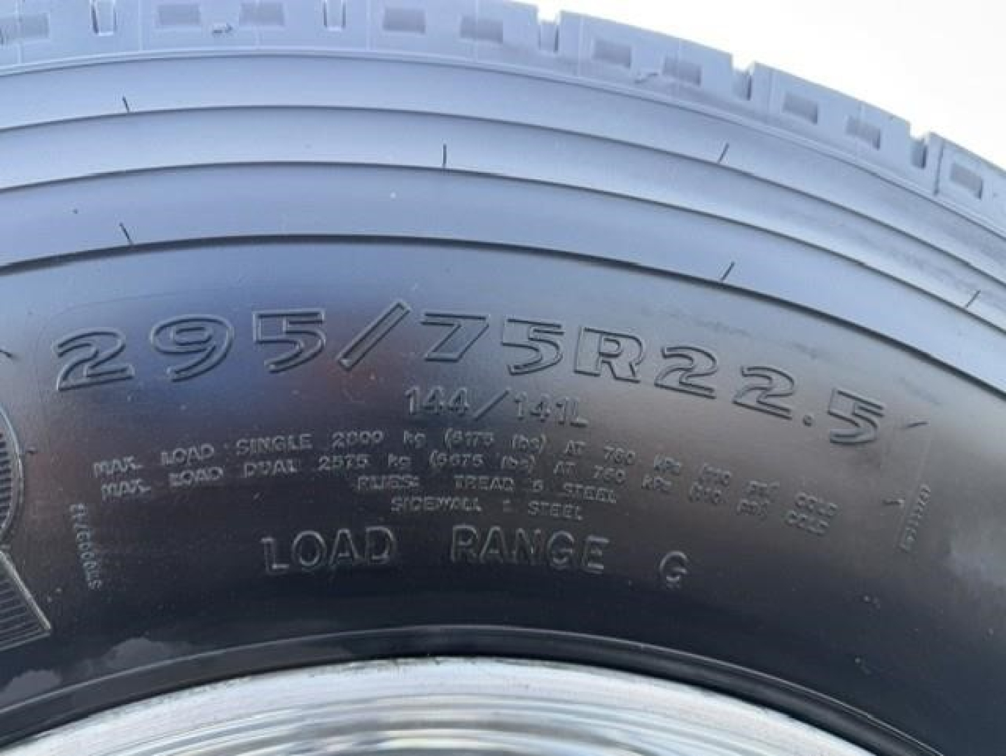 Tire sidewall showing size 295/75R22.5 on Freightliner Cascadia 126 wheel area.