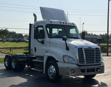 Freightliner Cascadia 126 day cab truck visible side showing cab and front grille with sleeper fairing.
