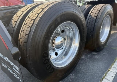 Dual rear axles with Goodyear tires and chrome wheels on a Freightliner Cascadia 126 truck, wheel rims visible; partial trailer hitch area and fender with markings.