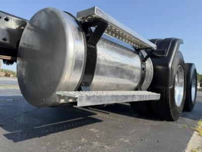 Aluminum cylindrical fuel tank or cross-rail on Freightliner Cascadia rear undercarriage with dual rear wheels and metal steps.