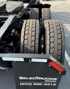 Freightliner Cascadia 126 chassis showing double rear tandem tires and part of the frame with a SelectTrucks sign in foreground.